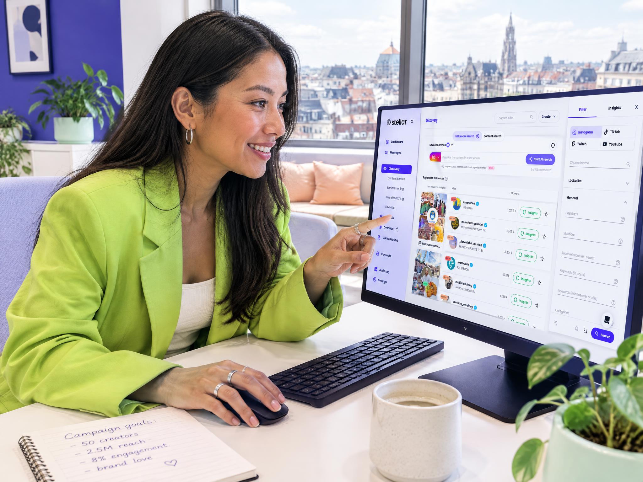 Woman at a desk pointing at an influencer search on the Stellar platform, with campaign goals noted in a notebook